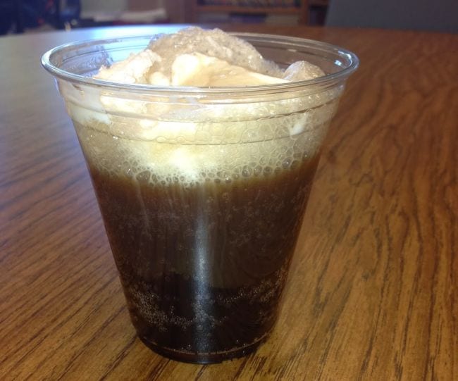 A root beer float in a clear plastic cup