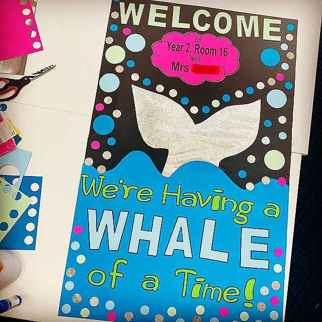 A door features blue water and a whale tail and says Welcome we're having a whale of a time.