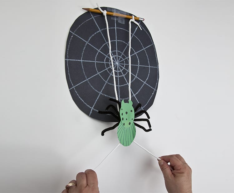 A halloween paper craft of a black spider web and a green spider