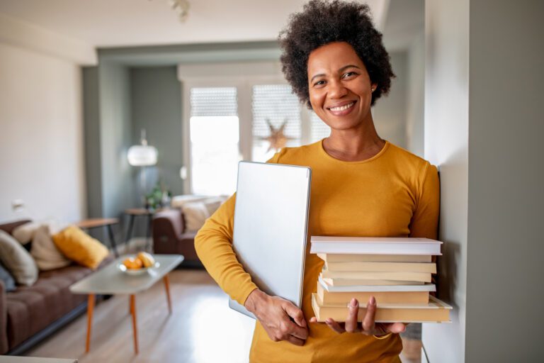 Portrait of woman holding books and laptop