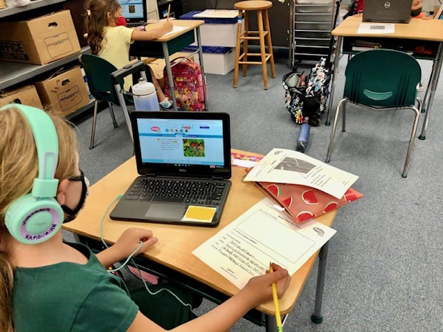 This student is researching the red fox on PebbleGo and writing down her findings.