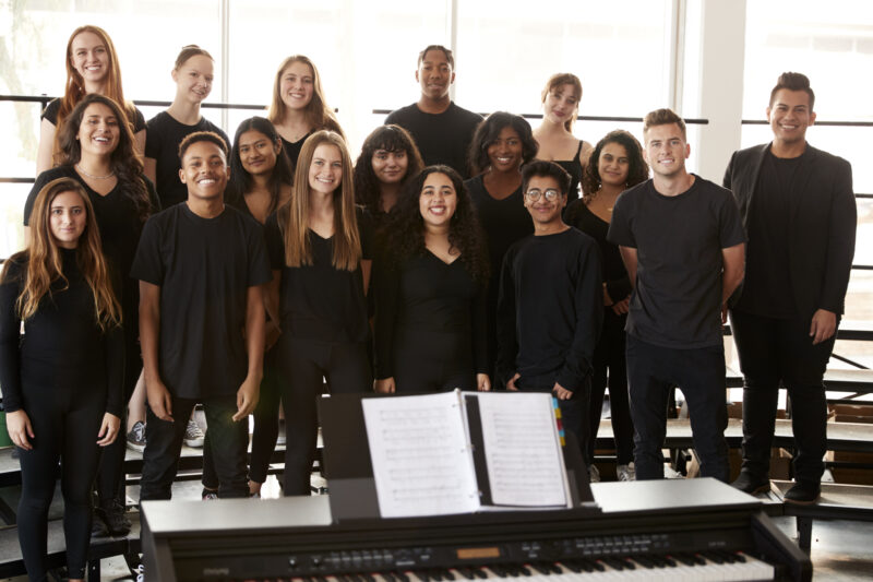 Portrait Of Male And Female Students Singing In Choir With Teacher At Performing Arts School