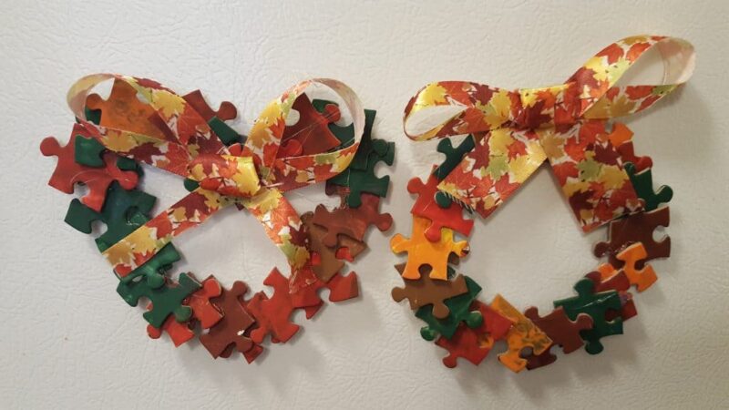 Two wreaths are made from orange, yellow, red, and green puzzle pieces.