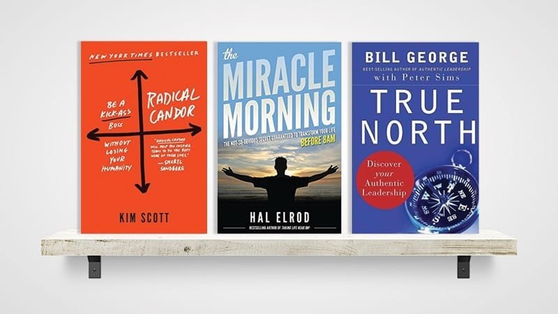 Three leadership books on a shelf.