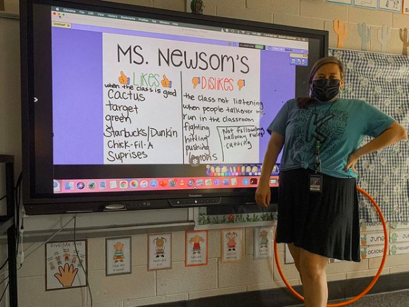 A teacher stands in front of projection screen