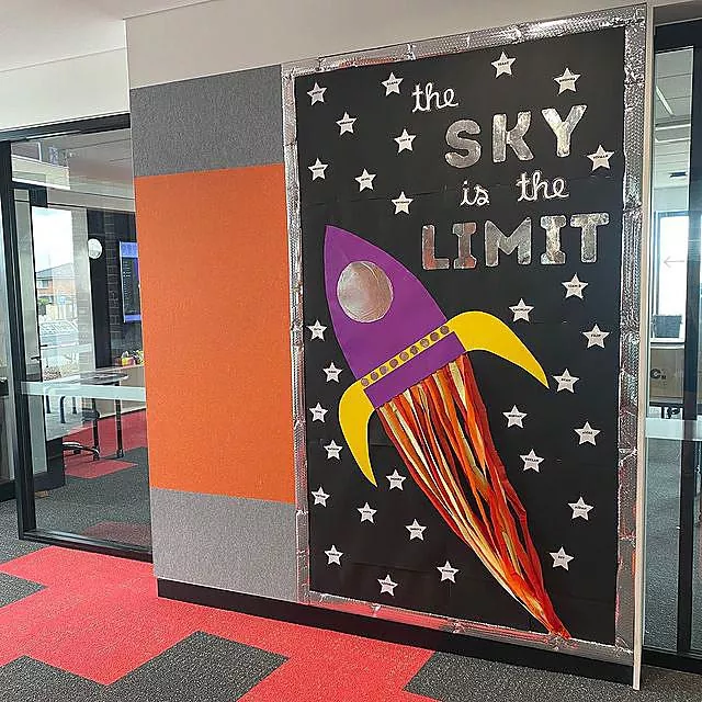 A door is decorated with a rocket ship and says the sky is the limit.