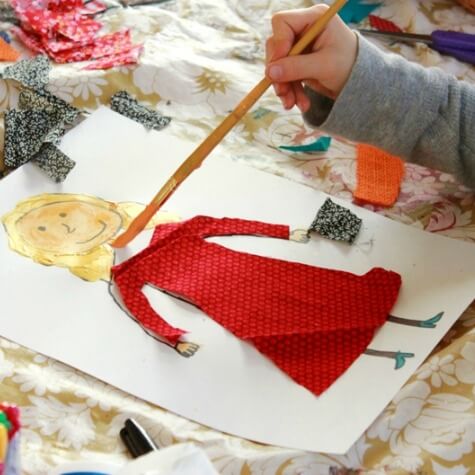 Child painting a person on paper, with a fabric scrap dress