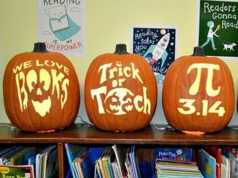 Three carved pumpkins lined up on a bookshelf