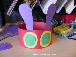 children's headband made from construction paper- red for the band, purple for the antennae and green and yellow for the eyes in this example of very hungry caterpillar activities. 
