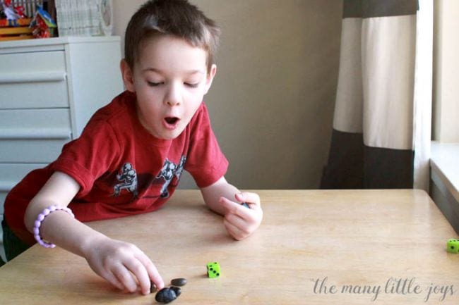 Young student rolling a dice and moving rock counters (Dice Games)