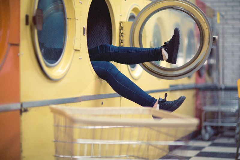 A pair of legs waving out of a dryer in a laundromat