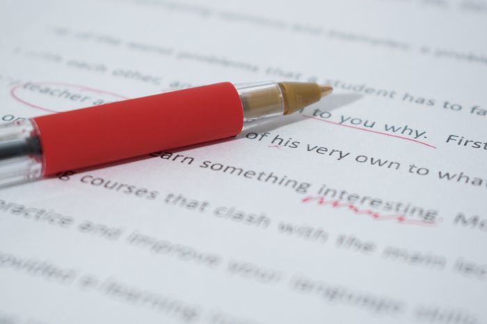 A red pen lying on a type-written sheet showing some corrections made by an editor.