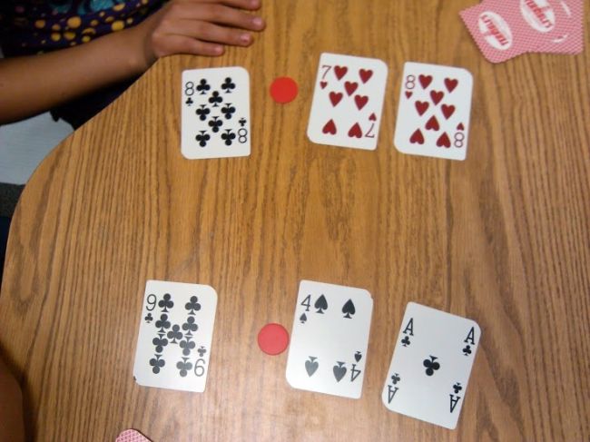 Playing cards laid out face up with red markers to turn them into decimals