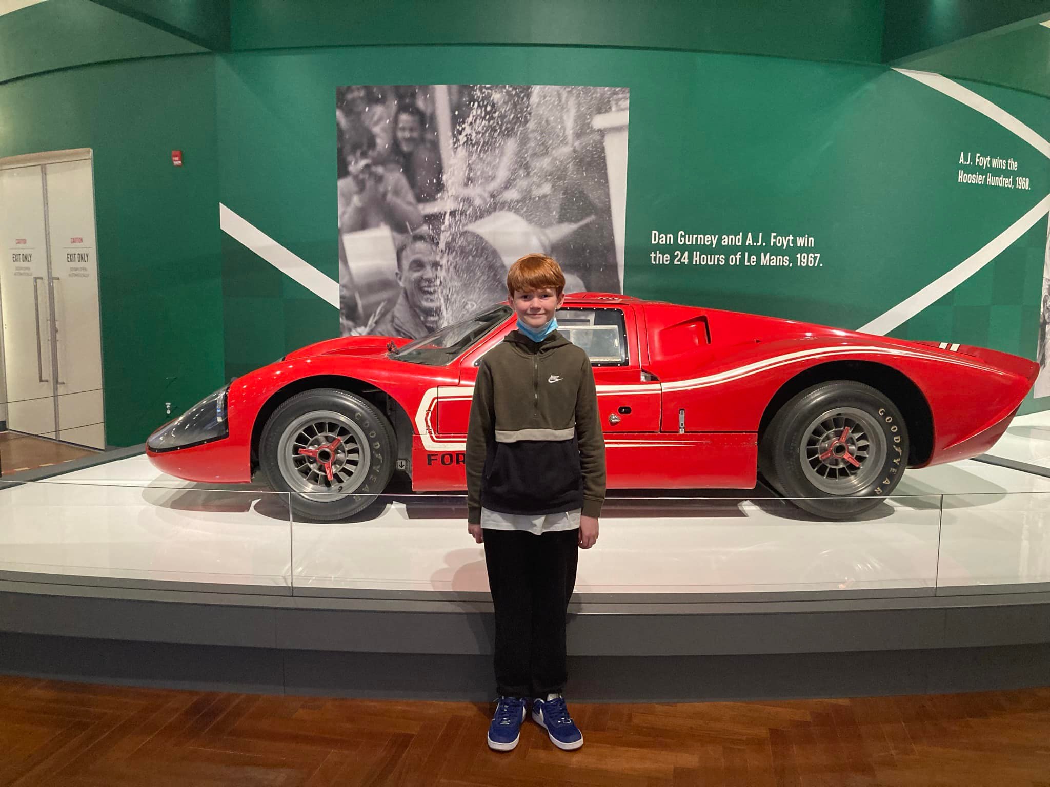 Boy standing in front of red sports car at Henry Ford Museum