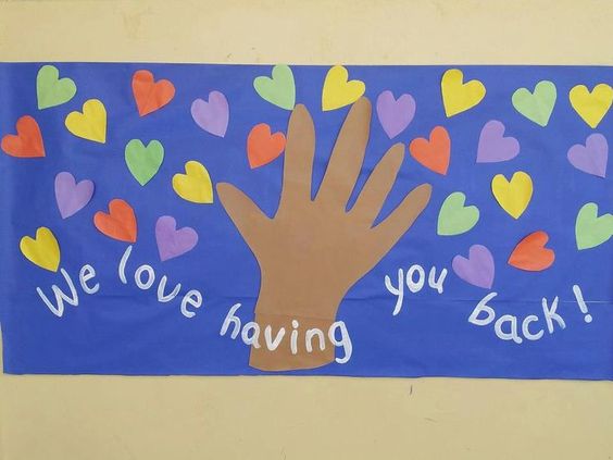 A bulletin board says we love having you back and has different colored hearts all over it.