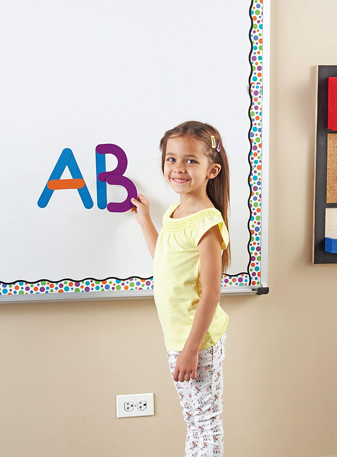 Child playing with magnetic letters on a whiteboard as an example of science activities for preschoolers