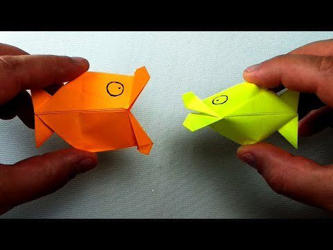 Hands are shown holding an orange origami fish and a neon yellow origami fish in this easy art project for kids.