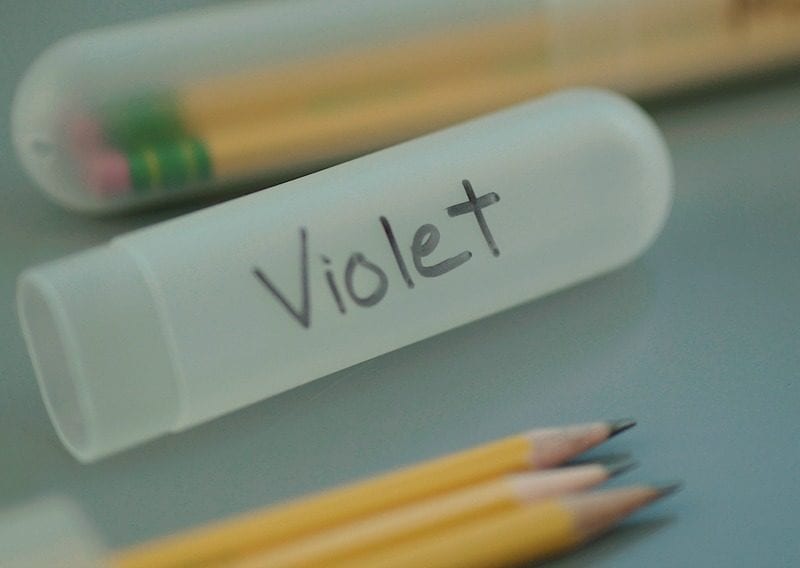 White toothbrush holder filled with pencils and labeled "Violet" 
