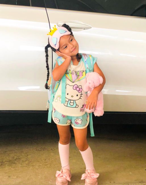 An adorable little girl is decked out in jammies, slippers and a sleep mask