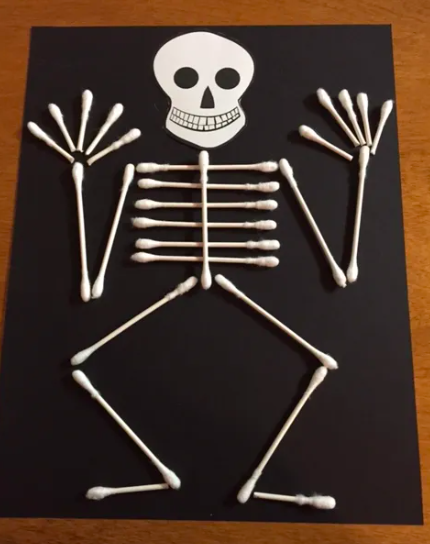 A jaunty skeleton made from Qtips glued to black paper as an example of Halloween Crafts for Kids 