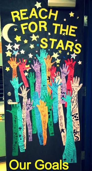 A door says Reach for the Stars. It features different colored arms all reaching up toward a moon and stars.