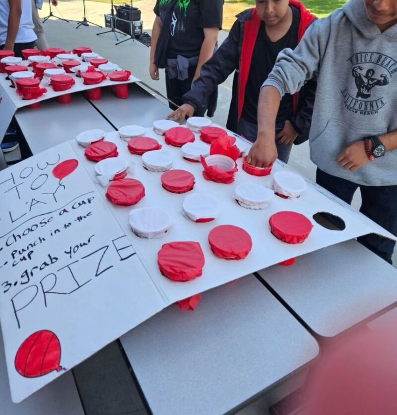 Students are lined up to punch through tissue paper on red cups to receive prizes as part of Red Ribbon Week activities