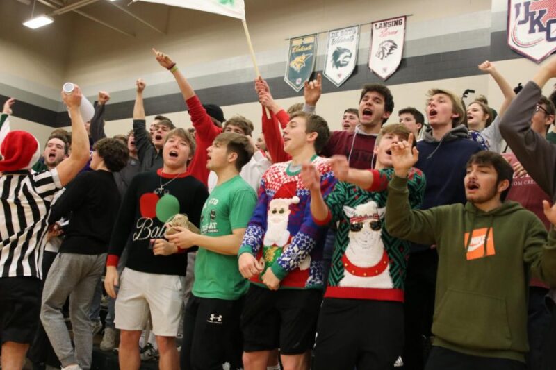 A group of students, some in ugly Christmas sweaters, participate in a school cheer