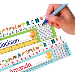 A hand holding a pen writes on a desk nameplate