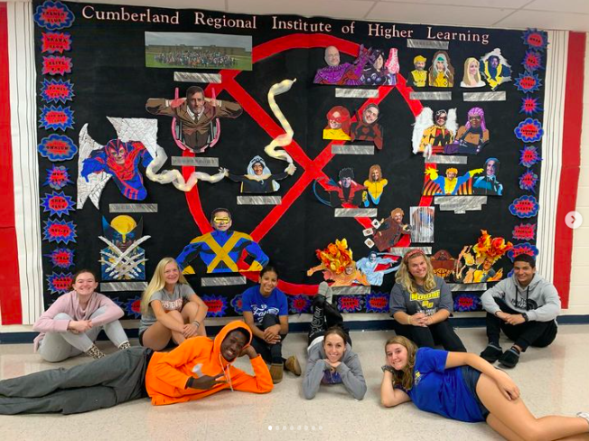 Students pose in front of a school spirit wall