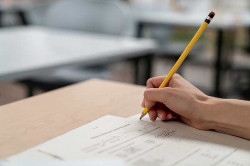 student hand holding a pencil taking a test